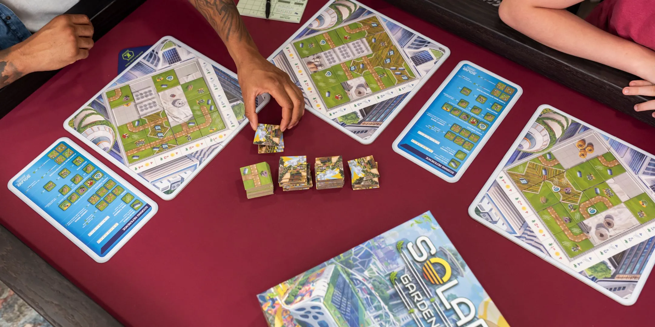 Một người chơi đang đặt những ô gạch thiết kế vườn và năng lượng trong board game Solar Gardens
