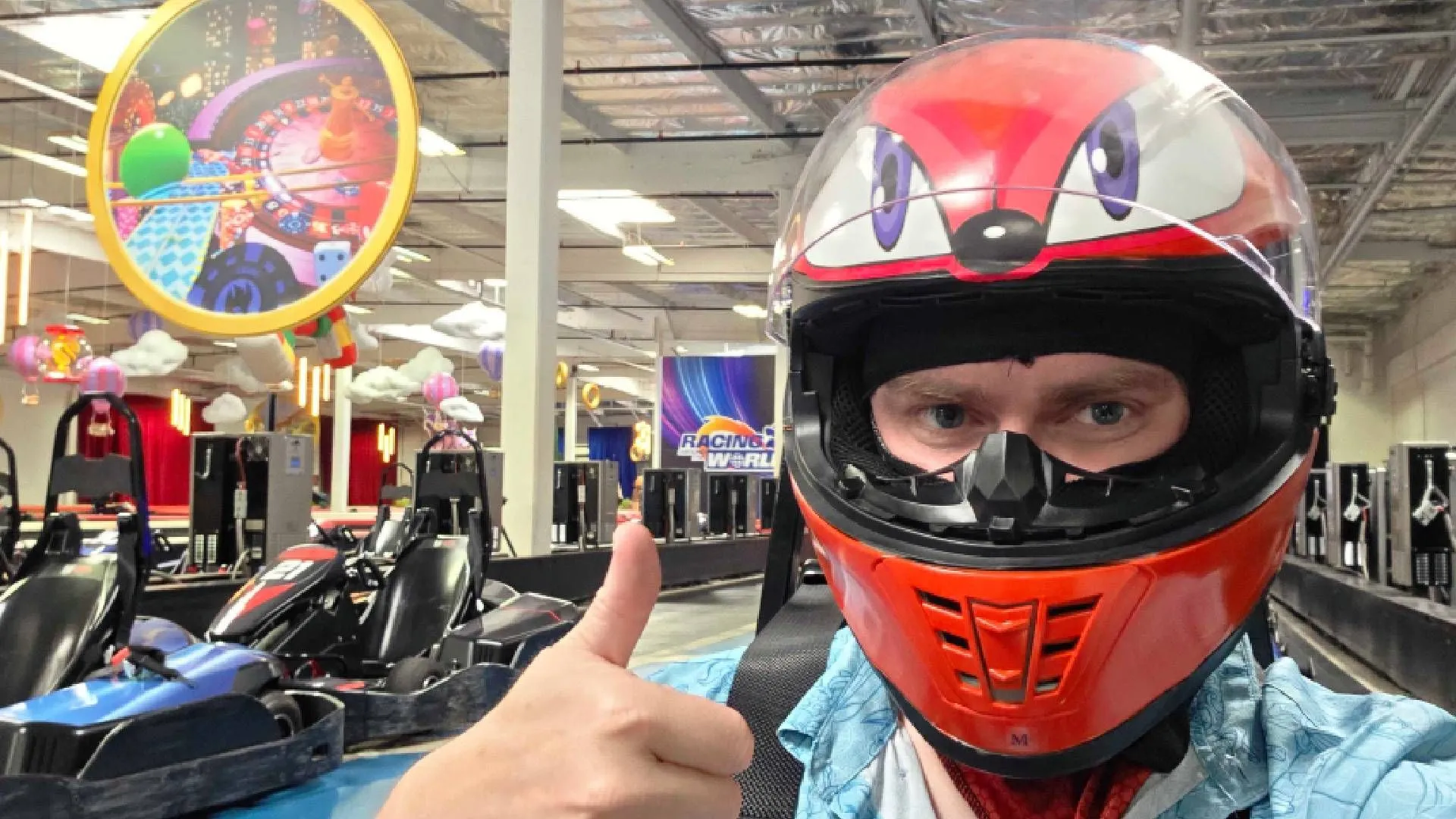 Người chơi giơ ngón cái trên xe go-kart tại đường đua K1 Speed được trang trí chủ đề Sonic, thể hiện sự phấn khích trong sự kiện Sonic Racing: Crossworlds.